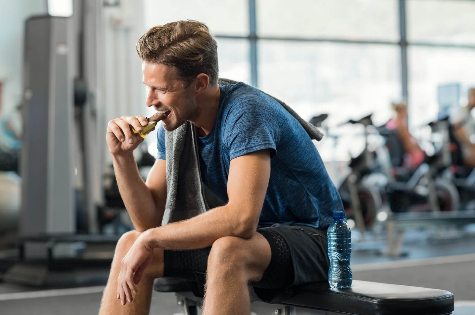 Mann isst einen Riegel im Fitnessstudio